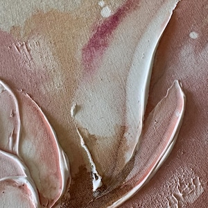 May include: A textured canvas painting featuring abstract shapes in shades of beige, cream, and dusty rose. Thick, raised white and light pink paint strokes create organic forms, accented by small splatters of deep magenta and brown paint.