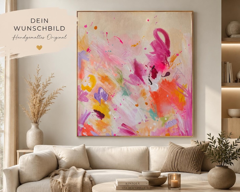 May include: A square abstract painting in a thin gold frame featuring vibrant splashes of hot pink, orange, yellow, and purple paint on a light beige background. The artwork displays energetic brushstrokes and splatters of color throughout.