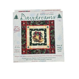 Puede incluir: Un kit de punto de cruz contado Dimensions Daydreams con un diseño de campanas de Navidad. El empaque muestra el proyecto terminado de 20 cm por 20 cm con un borde de cuadros rojos, hojas de acebo y las palabras Peace, Love, Magic, Hope, Wonder, Joy y Jolly Christmas.