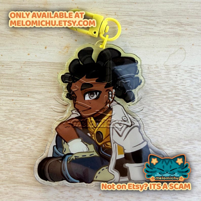 May include: A clear acrylic charm featuring a seated anime-style character with dark skin, black hair, and a white jacket. The charm has a yellow clasp and the text "ONLY AVAILABLE AT MELOMICHU.ETSY.COM" and "Not on Etsy? ITS A SCAM".