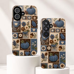 May include: Two phone cases featuring a patchwork design with a crochet-style texture. The pattern includes blue pumpkins, brown acorns, white and blue flowers, leaves, and hearts in a grid layout with dark brown and cream-colored square accents.