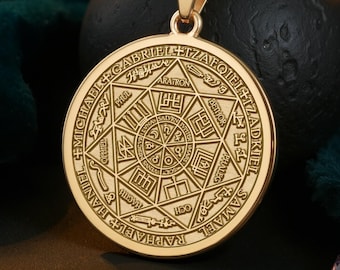 May include: Gold-colored pendant necklace with a detailed circular design. The pendant features intricate engravings of symbols and text. The necklace is displayed on a dark green velvet surface, with a black sphere in the background.