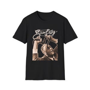 May include: Black t-shirt featuring a sepia-toned graphic of a person holding a snake, with the text "Straw Billy" in a stylized font. The design is centered on the front of the shirt.