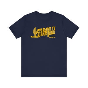 May include: Navy blue t-shirt with a yellow graphic of a cactus and the text "STRAWBILLY". Below the text is "03-PUNK, USA". The shirt has short sleeves and a crew neck.