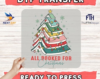 May include: A DTF transfer featuring a Christmas tree design made of books, decorated with colorful lights and a star. The text "ALL BOOKED FOR Christmas" is below the tree, with "READY TO PRESS" above a red banner.