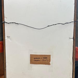 May include: Back of a framed artwork with a brown wooden frame. The artwork's backing is white with a label that reads "BARBARA A. PERRIN LAMBTON COUNTY". A black wire is strung across the back for hanging.