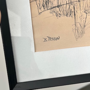 May include: A framed pen and ink drawing featuring a landscape scene with tall grasses and a fence. The artwork is signed "B. Perrin" in the lower right corner. The drawing is set against a tan background and framed in a black frame with a white mat.
