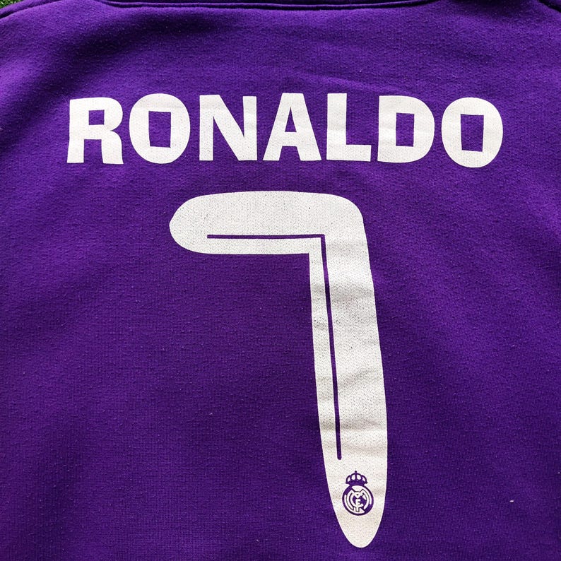 May include: Close-up of a purple jersey with the name "RONALDO" in white block letters across the back. Below the name is the number "7" in white, with a team logo at the bottom.