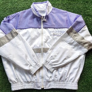 May include: A white and light purple windbreaker jacket with a full-length front zipper, a high collar, and elasticized cuffs and hem. The jacket features grey horizontal stripes on the sleeves and the text Courr&egrave;ges sport futur paris.