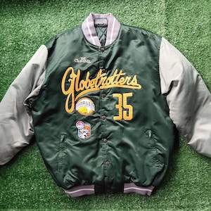 May include: A dark green satin bomber jacket with grey sleeves and a grey ribbed collar and cuffs. The front features yellow embroidered text reading Globetrotters, the number 35, and two circular patches with the text The Original and Harley.