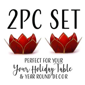 May include: Two red lotus-shaped candle holders with gold edging. The text "2PC SET" is above the candle holders. Below the candle holders is the text "PERFECT FOR YOUR Your Holiday Table & YEAR ROUND DECOR".