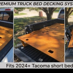May include: A premium truck bed decking system featuring light brown wooden panels with rectangular cutouts, designed to fit a 2024+ Tacoma short bed. The system covers the truck bed floor, providing a flat surface for storage and organization.