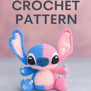 Peut inclure: Poupée Stitch crochetée, bleue et rose, avec de grandes oreilles et des yeux noirs. Le texte "PDF CROCHET PATTERN" est en haut. La poupée mesure 13 cm de haut.