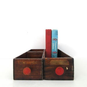 May include: Two wooden drawers with red knobs, sitting on a white surface. The drawers are empty, but there are two books behind them. The books are titled "The Companion Library" and "The Beauty of Nature".