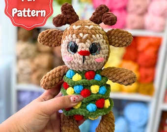 May include: A handmade crochet Christmas Tree Reindeer. The plush toy has brown antlers, a tan face, and a green body decorated with colorful pom-poms. The image includes the text "Pdf Pattern" and "Christmas Tree Reindeer".