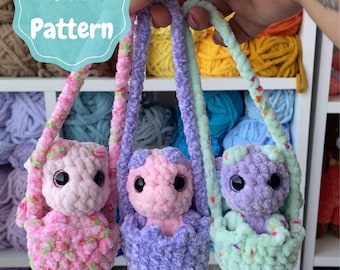 May include: Three handmade crochet dolls in pastel colors, each in a small carrier. The dolls are pink, purple, and mint green, with black eyes. The image includes the text "Pdf Pattern" in a teal circle.