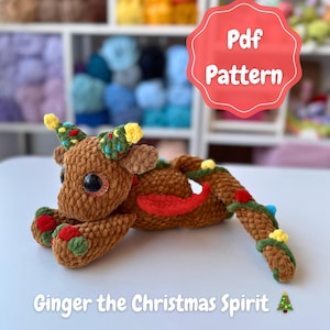 May include: A brown crocheted Christmas-themed creature with large black eyes, decorated with green, red, and yellow accents. The text "Pdf Pattern" is in a red bubble. The text "Ginger the Christmas Spirit" is below the creature.