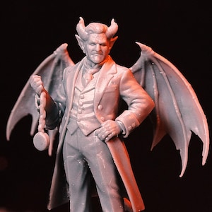 Puede incluir: Una figura gris de una figura parecida a un diablo con cuernos, alas y un traje, sosteniendo un reloj de bolsillo. La figura se encuentra sobre una base redonda con lo que parecen ser tuberías. El fondo es oscuro.