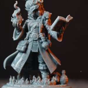 May include: A gray unpainted resin miniature of a spellcaster figure wearing a long coat, goggles, and a belt with pouches. The figure holds a sculpted flame in one hand and an open book in the other, standing on a circular base with flame details.