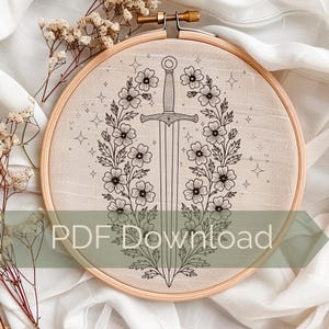 May include: Embroidered hoop art with a black and white floral and sword design. The central sword is framed by a floral wreath. The text "PDF Download" is displayed across the bottom of the image.