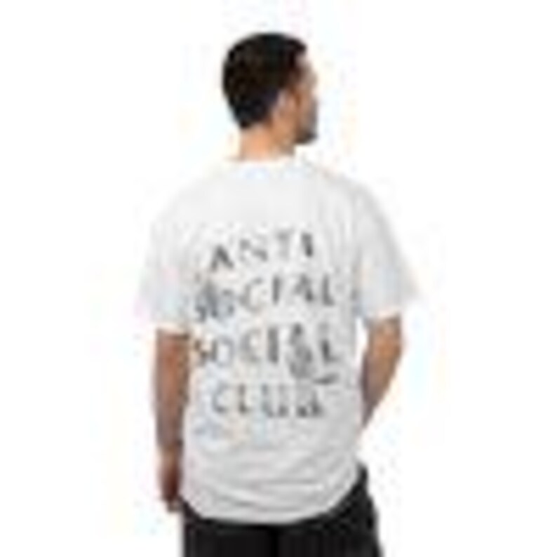 Puede incluir: Camiseta blanca con la inscripci&oacute;n "ANTI SOCIAL SOCIAL CLUB" impresa en negro descolorido en la espalda. El dise&ntilde;o de la camiseta tiene un aspecto ligeramente desgastado. La tela parece ser de algod&oacute;n.