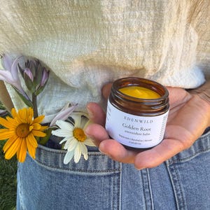 May include: A small amber glass jar of Edenwild Golden Root antioxidant balm with a white label, containing a bright yellow balm. The label reads: Edenwild Golden Root antioxidant balm, Replenish | Revitalize | Renew, 2 oz (57 g).