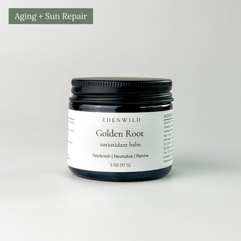 May include: A dark amber glass jar with a black screw-top lid, featuring a white label that reads Edenwild Golden Root antioxidant balm, Replenish | Revitalize | Renew, and 2 OZ (57 G). The text Aging + Sun Repair appears above the jar.