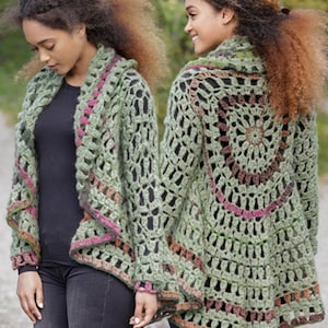 Op de afbeelding: Een groene gehaakte cardigan met een geometrisch openwerkontwerp. De cardigan heeft een cirkelvormig patroon op de rug en is afgewerkt met roze en bruine accenten. De mouwen zijn lang en de cardigan is aan de voorkant open.