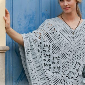 Op de afbeelding: Een lichtblauwe gehaakte poncho met een V-hals. De poncho heeft een open patroon met bloemmotieven. Het kledingstuk is gemaakt van een zacht, lichtgewicht materiaal, perfect om te dragen.