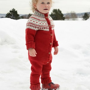 May include: A red knitted one-piece jumpsuit featuring a high collar and a button-down front. The upper chest and shoulders display a white and grey fair isle pattern. The garment has long sleeves with ribbed cuffs and matching red leather boots.