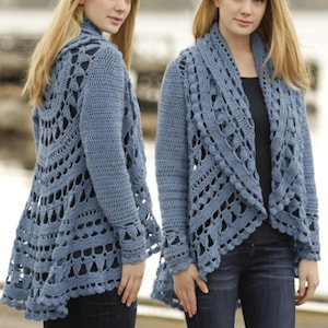 May include: A light blue crochet cardigan with an open, flowing design. The long-sleeved garment features intricate openwork patterns and a draped collar. The cardigan is shown on a person wearing dark blue jeans.