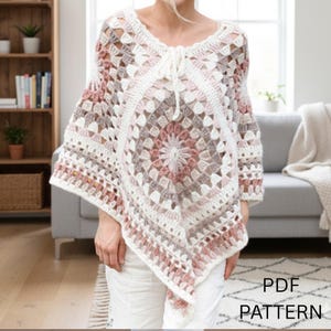 Può includere: Un poncho all'uncinetto color crema, rosa e grigio con un motivo quadrato. Il poncho ha uno scollo a V e una chiusura con coulisse. Il testo "PDF PATTERN" è visibile nell'angolo in basso a destra.