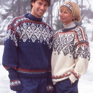 May include: A couple wearing matching Nordic-style sweaters and accessories. The sweaters are navy blue and cream with intricate white and red geometric patterns. The man wears a navy sweater and gloves, while the woman wears a cream sweater and a matching headband.