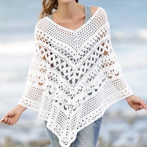 Peut inclure: Un poncho blanc en crochet à mailles ajourées avec un col en V. Le poncho présente un motif géométrique et est fait d'une matière douce et légère. Le vêtement est conçu pour être porté par-dessus d'autres vêtements.