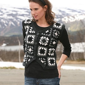 May include: A dark grey crochet vest with a button-up front. The vest features a square pattern in shades of grey and white. The vest is worn over a black long-sleeved top.