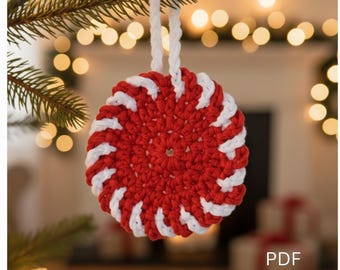May include: A red and white crocheted ornament with a spiral design, hanging from a white cord. The ornament is round and resembles a peppermint candy. The text "PDF PATTERN" is visible in the lower right corner. The ornament is hanging from a green pine branch.