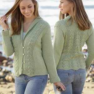 May include: A light green cardigan with a hood and button closure. The cardigan features a decorative openwork design along the front and back. The model is wearing blue jeans.