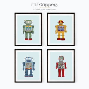 May include: Four framed prints featuring colorful robot illustrations. Each robot has a unique design with details like antennas, gears, and various body shapes. The robots are set against a light blue background, with the text "LITTLE Grippers STORE ORIGINAL PRINTS" at the top.