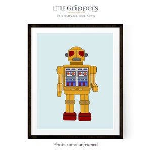 May include: Framed print featuring a yellow robot illustration with red and blue accents. The robot has a retro design, with rectangular eyes and a boxy body. The background is a light blue color. The text "Prints come unframed" is at the bottom.