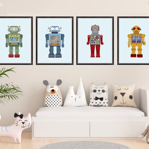 May include: Four framed art prints featuring colorful robot illustrations. Each robot has a unique design with different colors, including green, blue, red, and yellow. The prints are displayed above a white bed with decorative pillows.