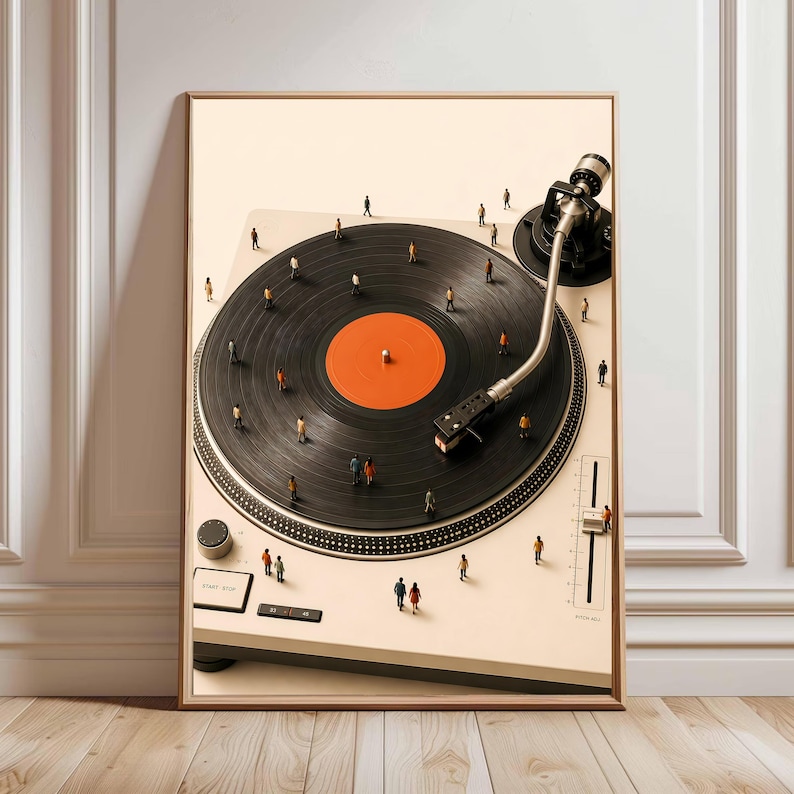 May include: A framed wall art print featuring a high-angle view of a cream-colored turntable with a black vinyl record. The record has a bright orange center label. Tiny miniature figures of people are standing across the surface of the record.