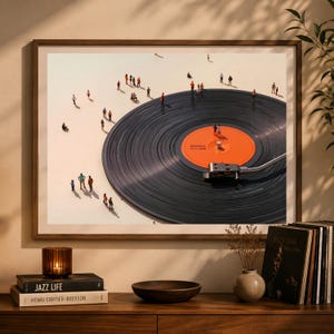 May include: A framed art print featuring a large vinyl record with tiny figures scattered across its surface and the surrounding area. The record has an orange label with text. The artwork is displayed on a wooden cabinet with books, a candle, and a small vase.