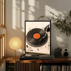 May include: A framed art print featuring a high-angle view of a white turntable with a black vinyl record. The record has a bright orange center label. Tiny miniature figures are scattered across the surface of the record and the turntable base.