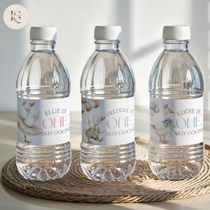 May include: Three clear plastic water bottles with white caps and labels. Each label features a cartoon goose and the text "Ellie is One Silly Goose", "Freddie is One Silly Goose", and "Eddie is One Silly Goose". The bottles are on a woven mat.