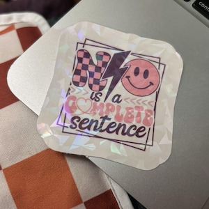 Può includere: Un adesivo olografico quadrato con una lettera N a scacchi neri e rosa, un fulmine nero e una faccina sorridente rosa. Il testo "No is a COMPLETE sentence" è scritto in un mix di caratteri in grassetto, ondulati e corsivi entro una cornice.