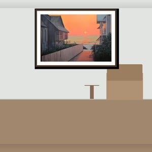 May include: A framed landscape painting showing a coastal scene at sunset. The artwork features a house, a white fence, and a path leading to the ocean under an orange and yellow sky. The frame is dark brown.