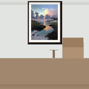 May include: A framed landscape painting shows a tranquil coastal scene with a reflective body of water. The sky shifts from pink and yellow to blue, with dark clouds. The painting is displayed on a light grey wall.