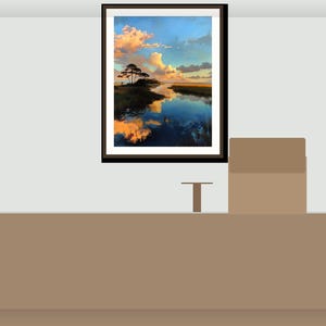 May include: A framed landscape art print depicting a tranquil coastal scene with a reflective body of water, silhouetted trees, and a vibrant sky in shades of blue, orange, and yellow. The artwork is displayed on a light grey wall.