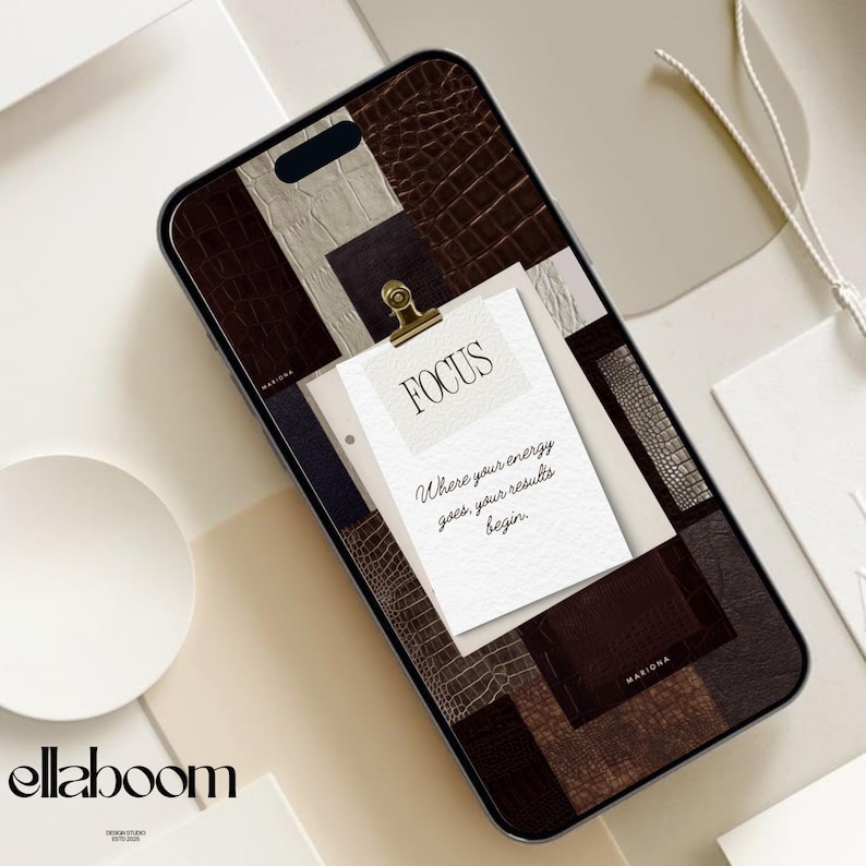 Op de afbeelding: Smartphonehoesje met een patchworkontwerp van bruine, beige en donkerbruine imitatieleertexturen. Een klein papiertje met het woord "FOCUS" en de quote "Where your energy goes, your results begin" wordt vastgehouden door een gouden clip.