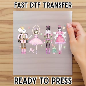 May include: A ready-to-press DTF transfer sheet featuring watercolor illustrations of characters from The Nutcracker ballet. The sheet includes a mouse king, a ballerina, a nutcracker, and a fairy, all in pink and green. The text "FAST DTF TRANSFER" and "READY TO PRESS" are at the top and bottom.